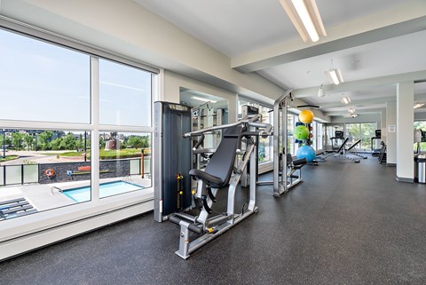A gym with a view of a pool and trees.