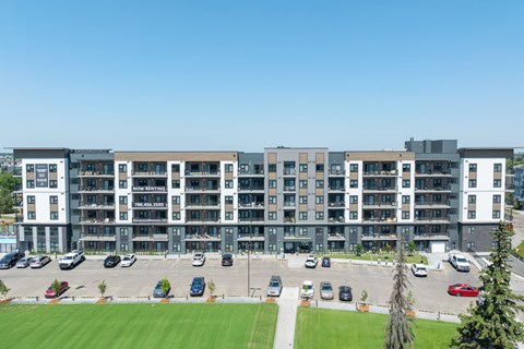 A modern apartment complex with a parking lot in front.