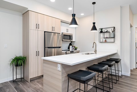 A kitchen with a white countertop and black bar stools.