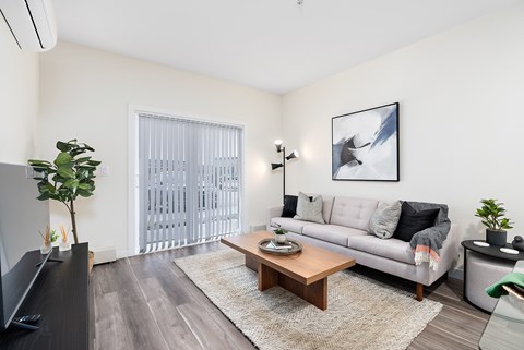 A living room with a grey couch, a wooden coffee table, and a flat screen TV.