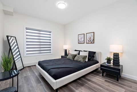 A bedroom with a large bed and a small table with a plant on it.