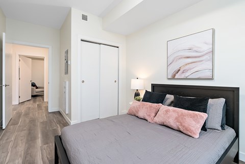 A bedroom with a large bed and a painting on the wall.
