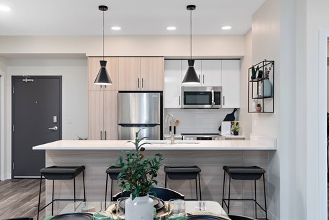 A modern kitchen with a white countertop and black bar stools.