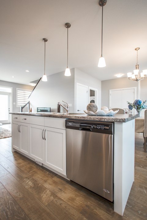 A modern kitchen with a stainless steel dishwasher and wooden flooring.