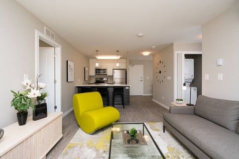a living room with a couch and a yellow chair in front of a kitchen