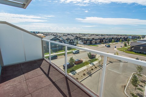 A balcony overlooks a parking lot and a residential area.