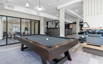A pool table is in the middle of a room with a glass wall.