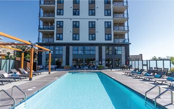 A large swimming pool in front of a multi-story apartment building.