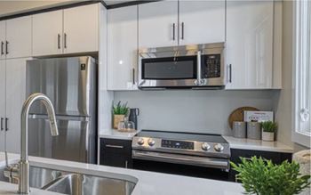 A modern kitchen with a stainless steel refrigerator, microwave, and oven.