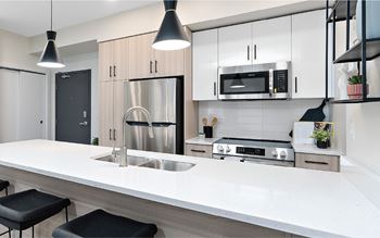 A modern kitchen with a stainless steel refrigerator, microwave, and oven.