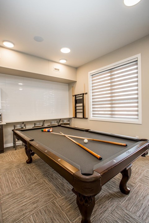 A pool table with a brown cloth and two pool cues.