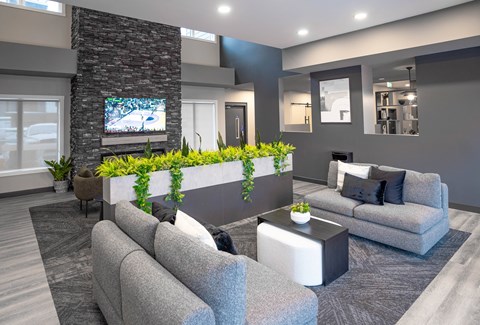 A modern living room with grey couches and a stone pillar.