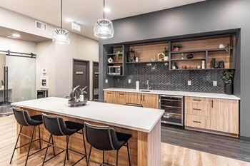 A modern kitchen with a white countertop and black chairs.