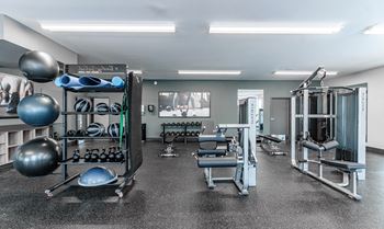 A gym with a variety of equipment including weights and exercise balls.