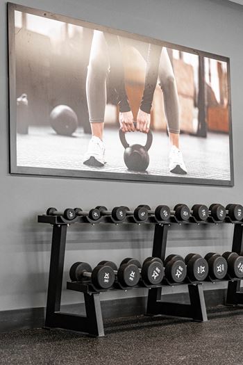 A person is lifting a kettlebell in a gym.