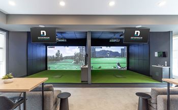 A room with a Devereaux sign on the wall and a large screen showing a golf game.
