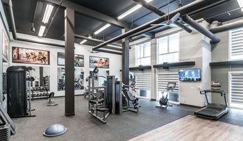 A gym with a variety of equipment including treadmills, weights, and exercise machines.