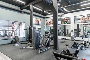 A gym with a variety of equipment including treadmills, weights, and exercise machines.