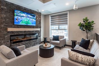 A modern living room with a stone fireplace and a flat screen TV mounted above it.