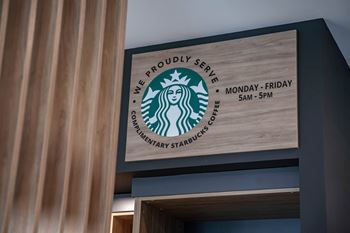 A Starbucks sign that says "We Proudly Serve Departmentary Starbucks Co." is on a wall.