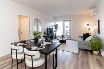 A modern dining room with a black table and white chairs.at Vibe Apartments at Arbour Lake, Calgary, AB T3G 4J2  