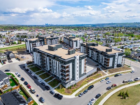 A large building complex with a parking lot in front. at Vibe Apartments at Arbour Lake, Alberta