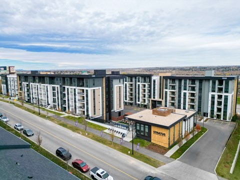 A modern building with a yellow sign that reads "STRATUR" is surrounded by cars and other buildings.