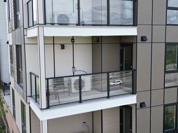 A modern apartment building with a balcony and glass railings.