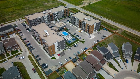 A bird's eye view of a residential area with apartment buildings, houses, and a swimming pool.