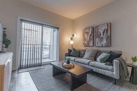 A living room with a grey couch, a coffee table, and two framed pictures on the wall.