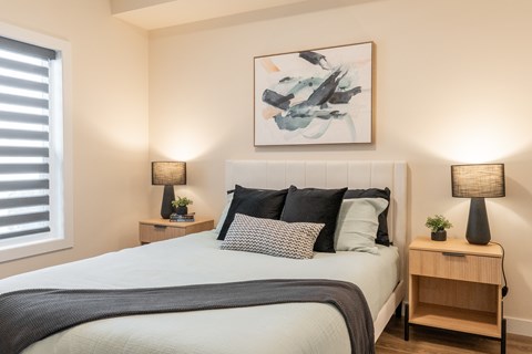 A bedroom with a large bed and two lamps on side tables.