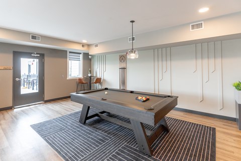 A pool table is in the middle of a room with a striped rug.