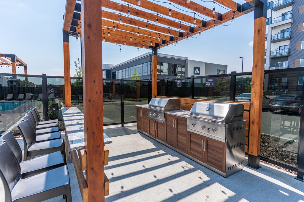 A wooden pergola with a grill underneath it.