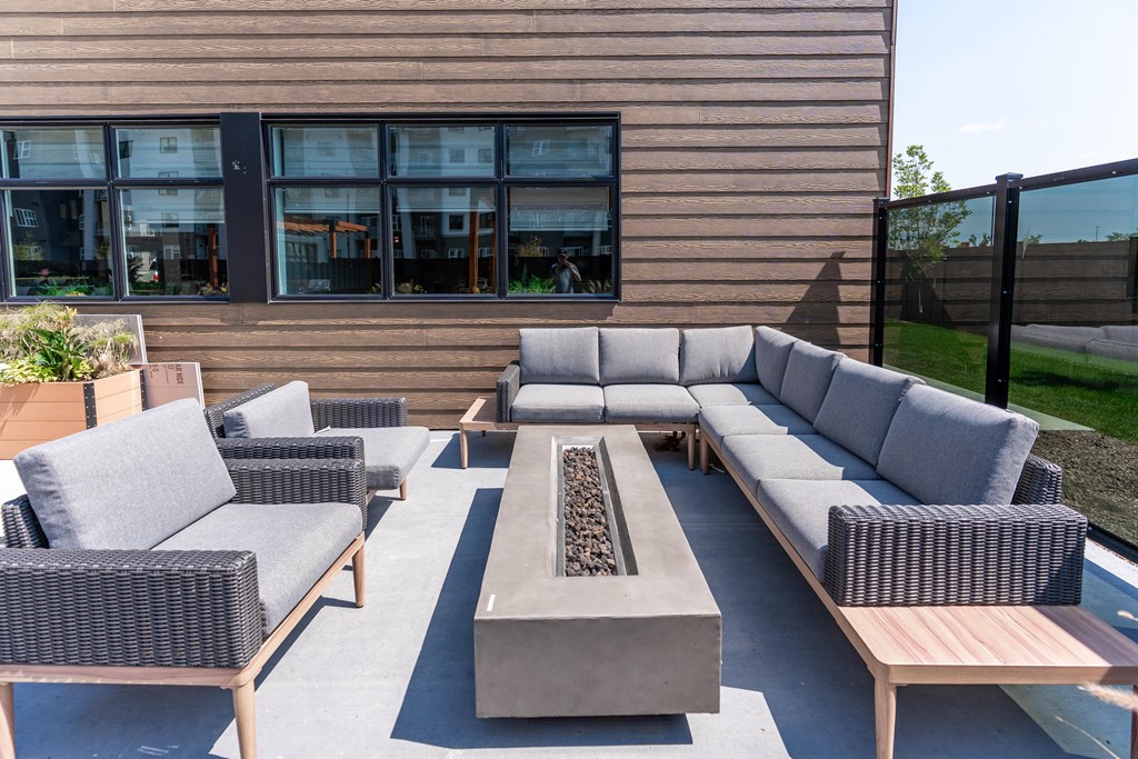A patio with grey furniture and a fire pit.