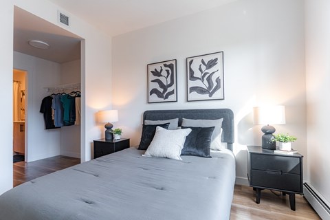 A bedroom with a large bed and two side tables with lamps.