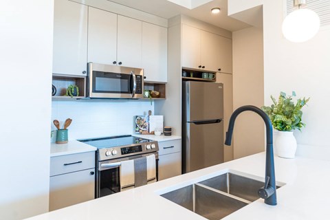 A modern kitchen with a stainless steel sink and refrigerator.