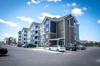 A large apartment building with cars parked in front.