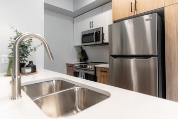 A modern kitchen with a stainless steel refrigerator and a white sink.
