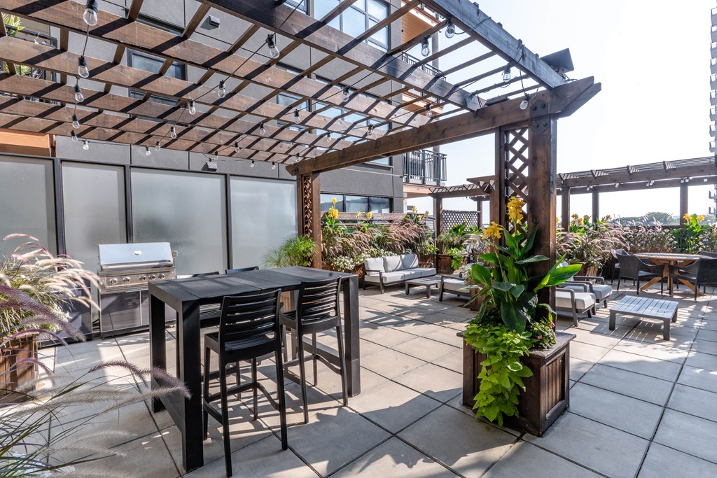 A patio with a table and chairs under a wooden pergola.