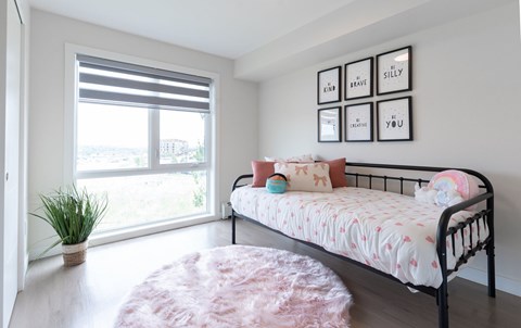 A bedroom with a bed, a potted plant, and pictures on the wall.