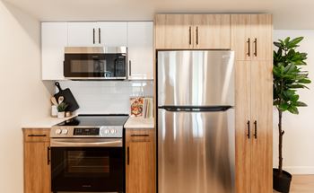 A modern kitchen with a stainless steel refrigerator, microwave, and oven.