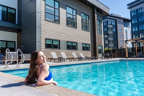 A Woman In a Blue Bikini Sits By a Pool at Podium Apartments, Alberta, T2E 7J2