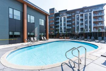 A swimming pool with a metal ladder in front of a building. at Vibe Apartments at Arbour Lake, Alberta