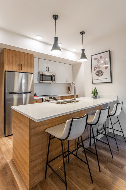 A kitchen with a white countertop and wooden cabinets. at The Artisan at Rangeview, Calgary, Alberta