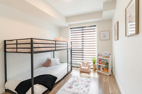A bedroom with a bunk bed and a small table with a plant on it.