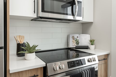 A modern kitchen with a black stove top and white countertops.
