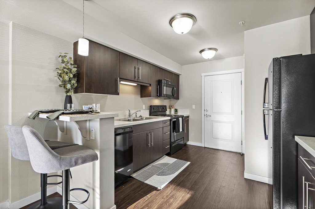 A kitchen with a black fridge and a white chair.