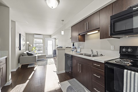 A modern kitchen with dark wood cabinets and a black microwave.