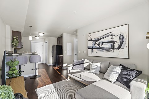 A modern living room with a grey couch and a large abstract painting on the wall.