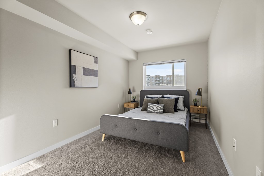 A bedroom with a bed, nightstands, and a window.